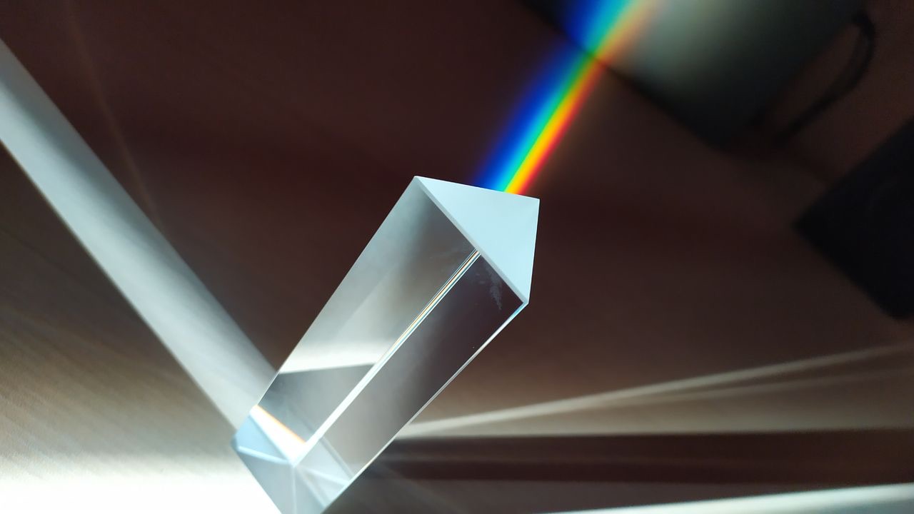 White light passing through a glass triangular prism and splitting into a rainbow spectrum.